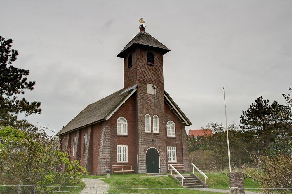 Het Vredeskerkje in Bergen aan Zee, een klein bakstenen kerkje met een houten toren tussen de bomen